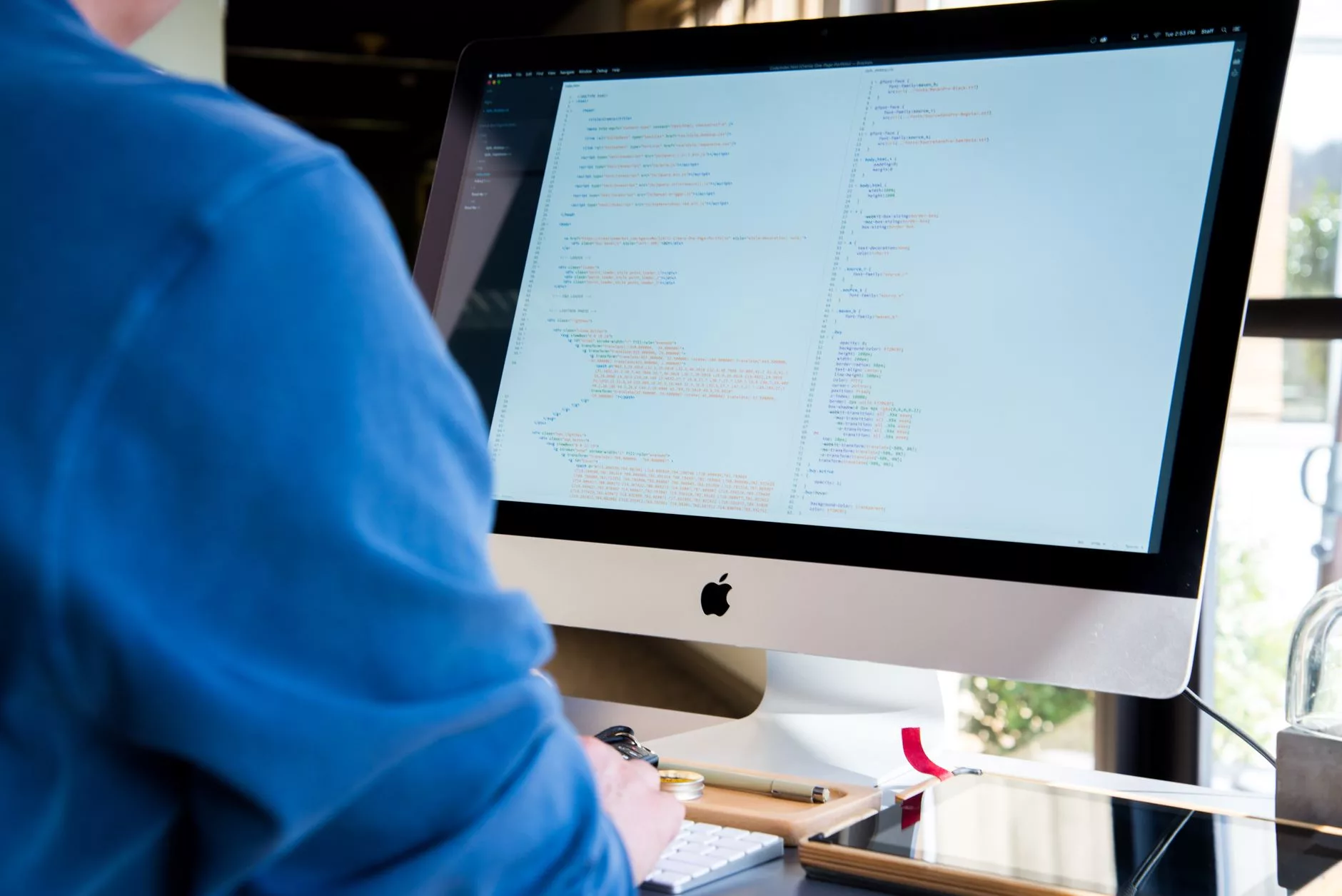 Web developer configuring a custom website layout on a dual-monitor desktop setup.