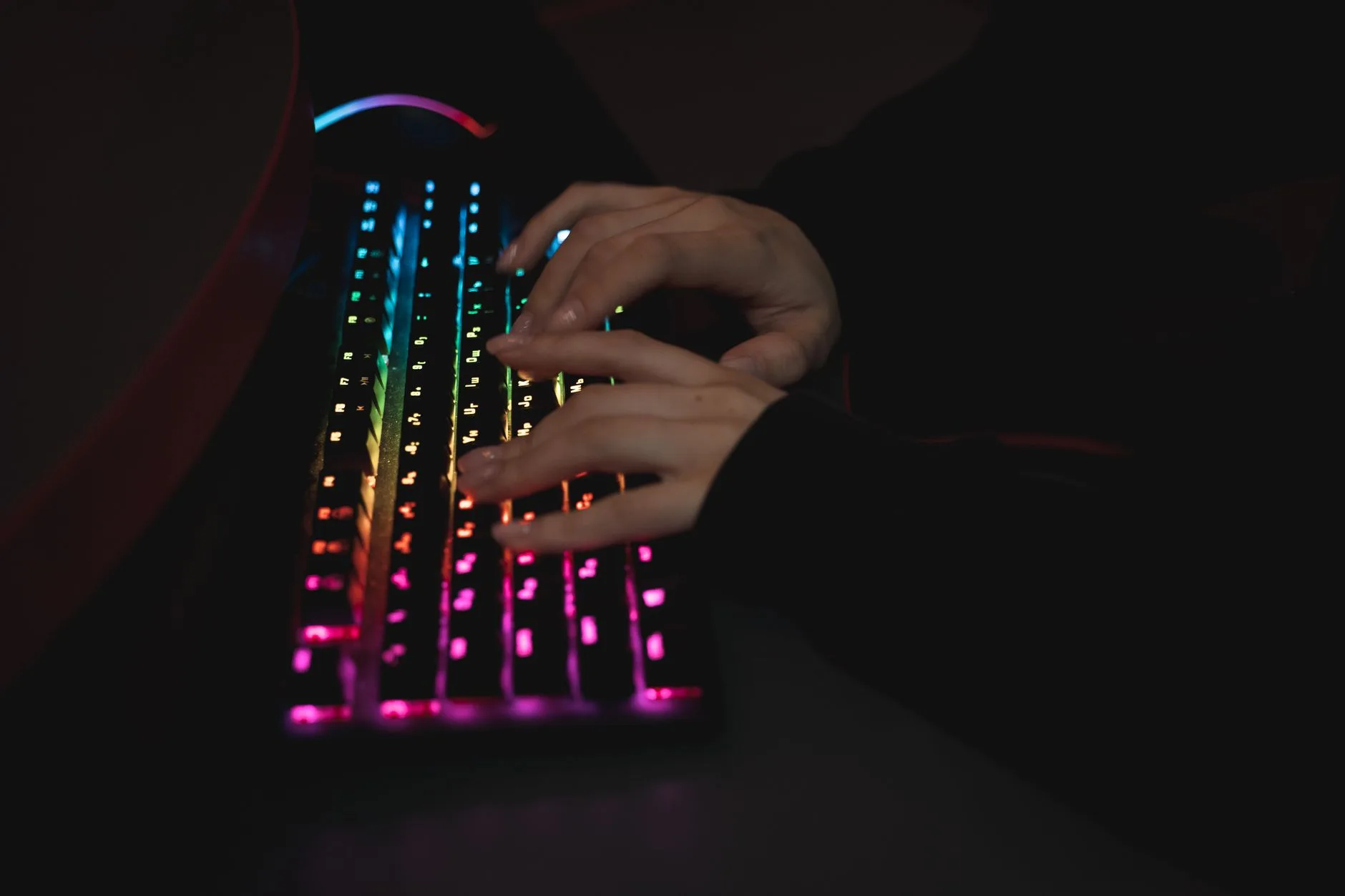 Developer writing code on a mechanical keyboard with glowing keys