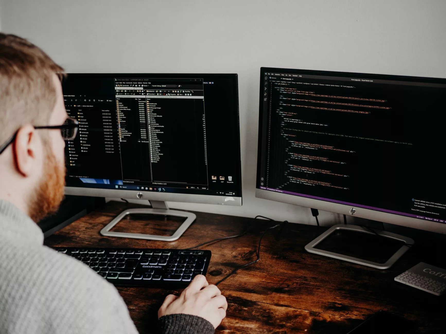 software engineer reviewing website code and technical parameters on dual screens