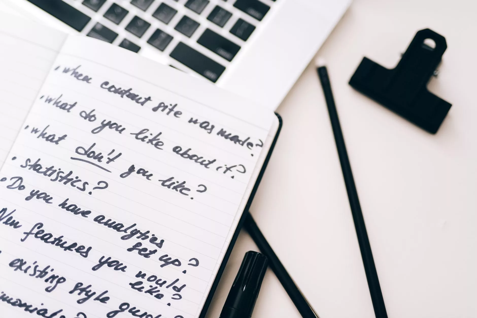 laptop displaying data analytics on desk with a notebook and pen