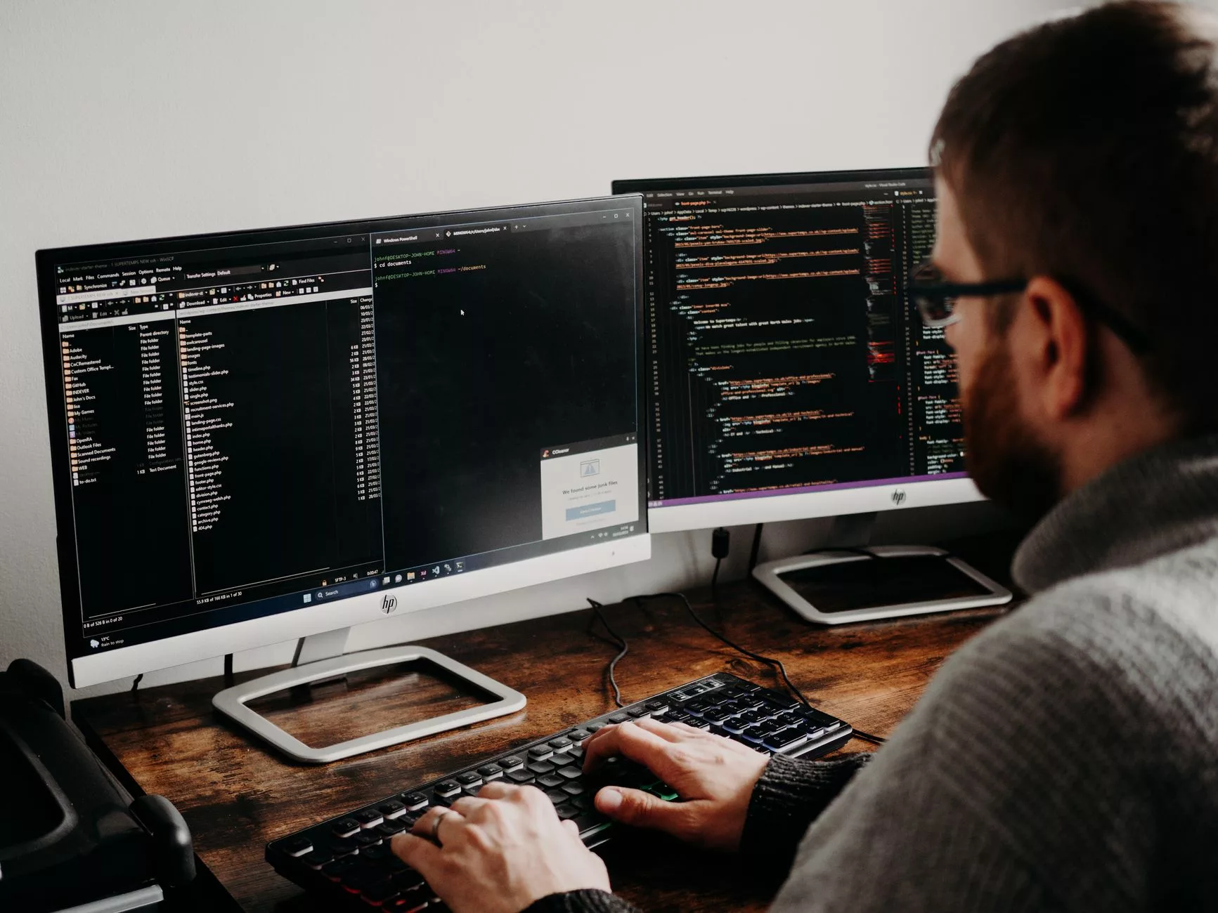 a web developer typing code on dual monitors at a modern desk